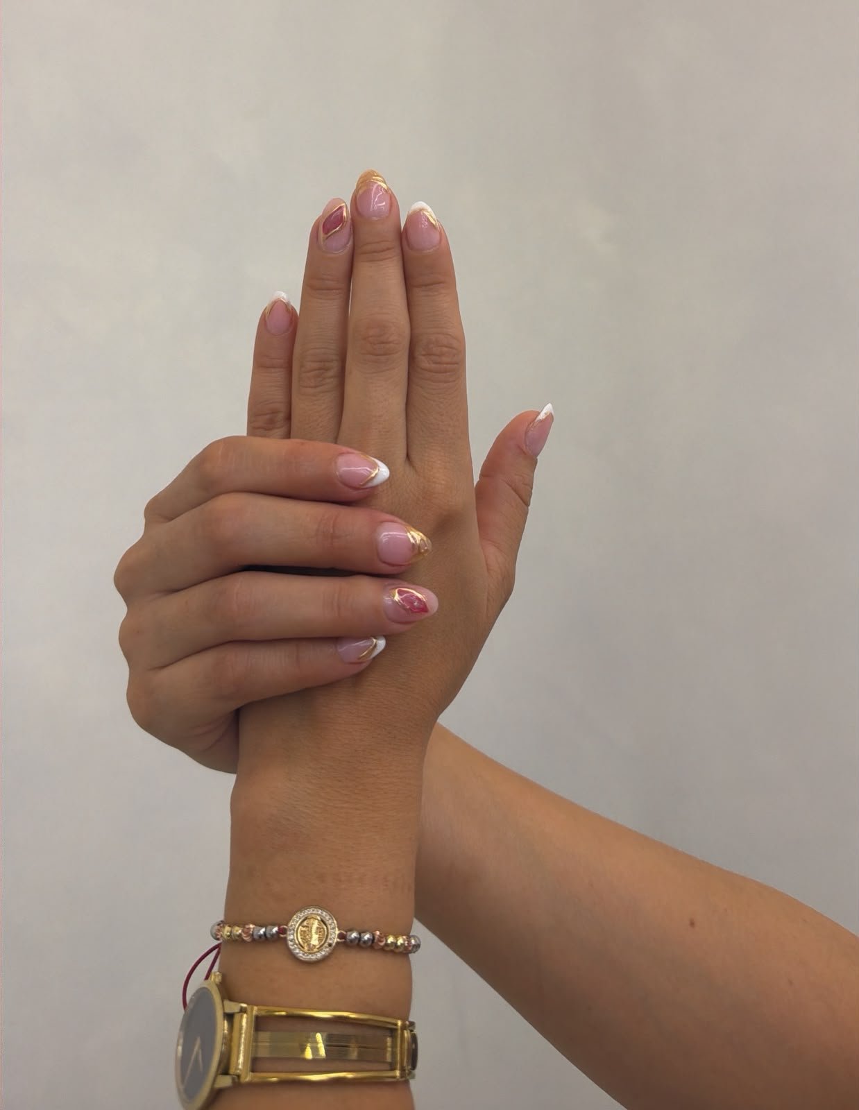 Uñas almendradas con francés blanco y detalles dorados y rosados